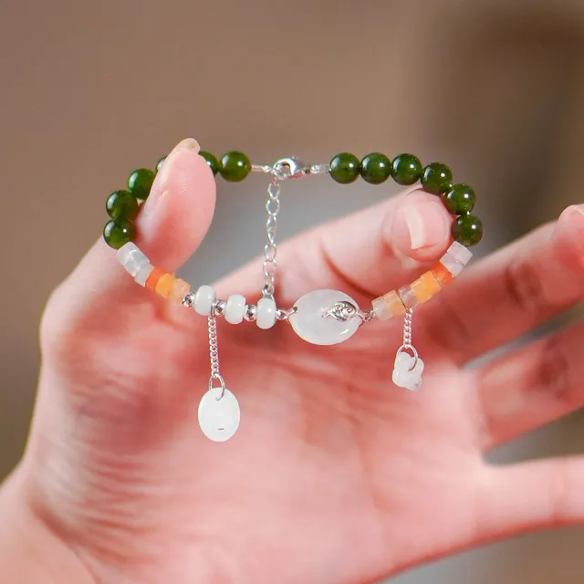 Bàn tay nâng vòng Thiên Ân: ngọc phỉ thuý xanh đậm, đồng điếu ngọc trắng, đá bánh xe cam và charm rơi